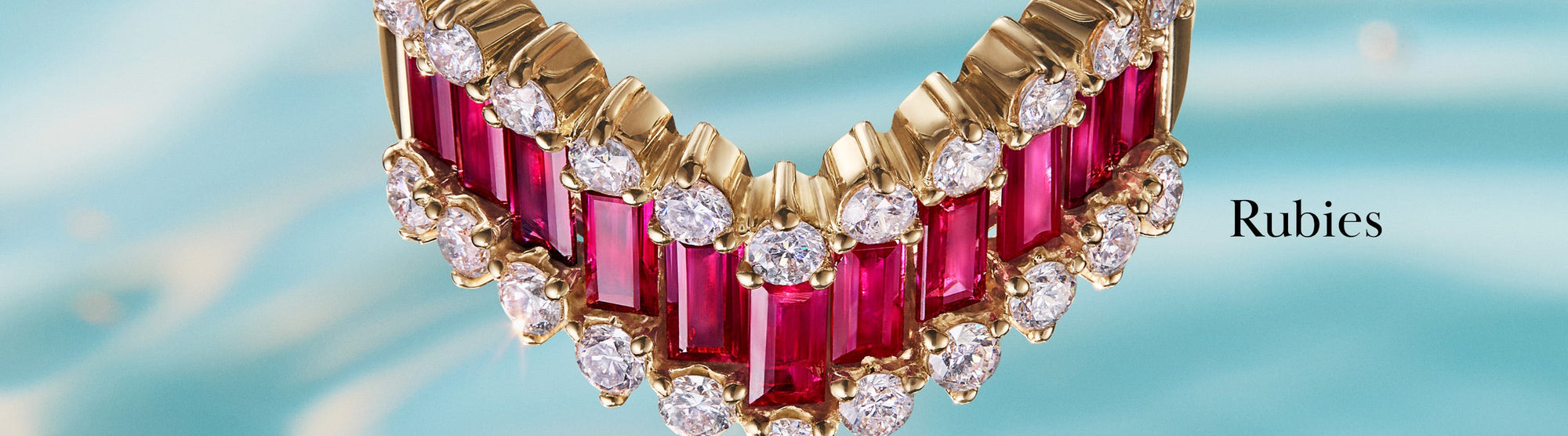 A gold necklace with a teardrop-shaped pendant featuring red rubies and diamonds is shown against a soft blue and pink gradient background. The word Rubies appears to the right.