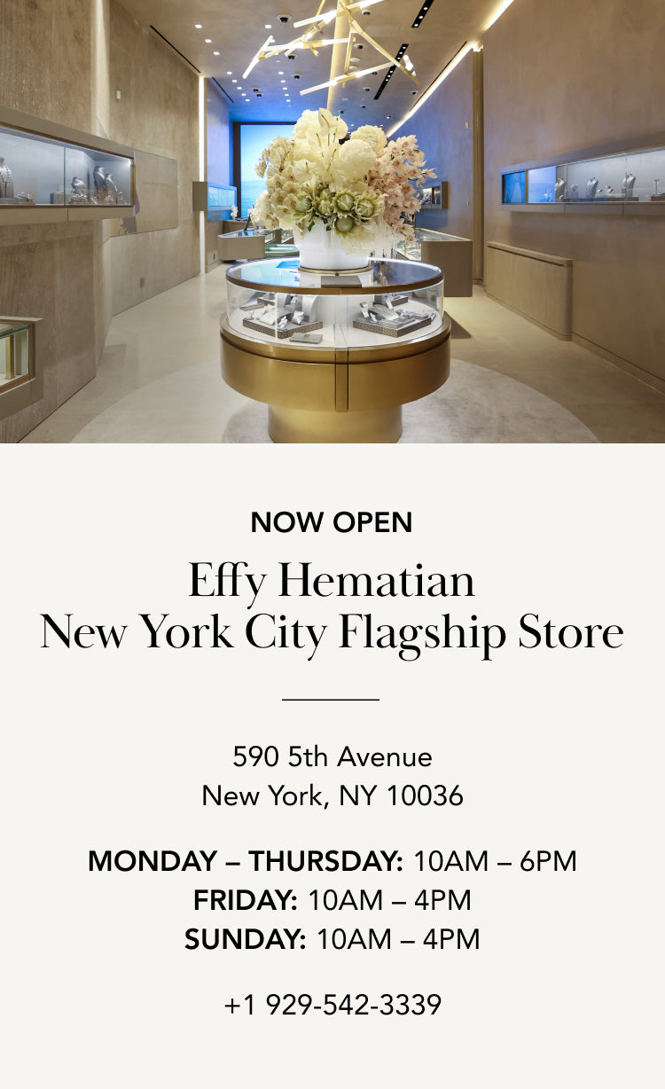 Interior of a modern jewelry store with glass display cases, large flower arrangement, and text announcing the opening of Effy Hematian’s NYC flagship store, including address, hours, and contact number.