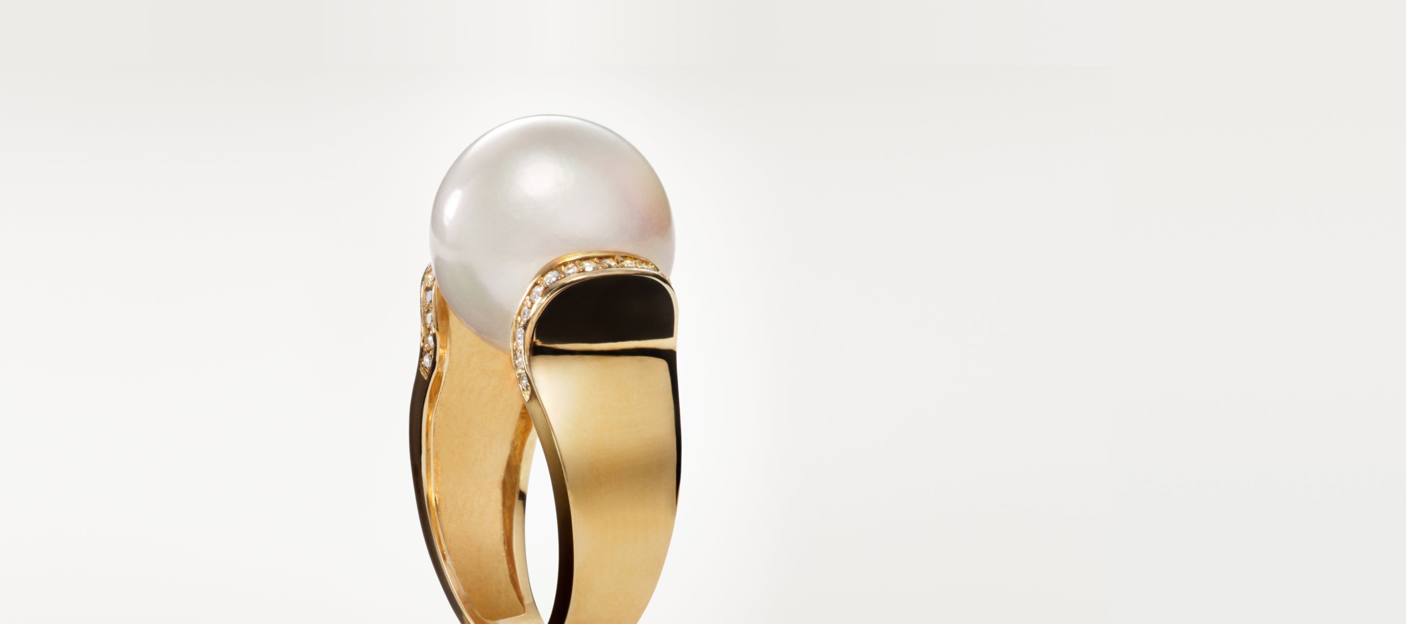 A gold ring featuring a large white pearl set on top, accented with small diamonds and black enamel detailing on the band, shown against a plain white background.