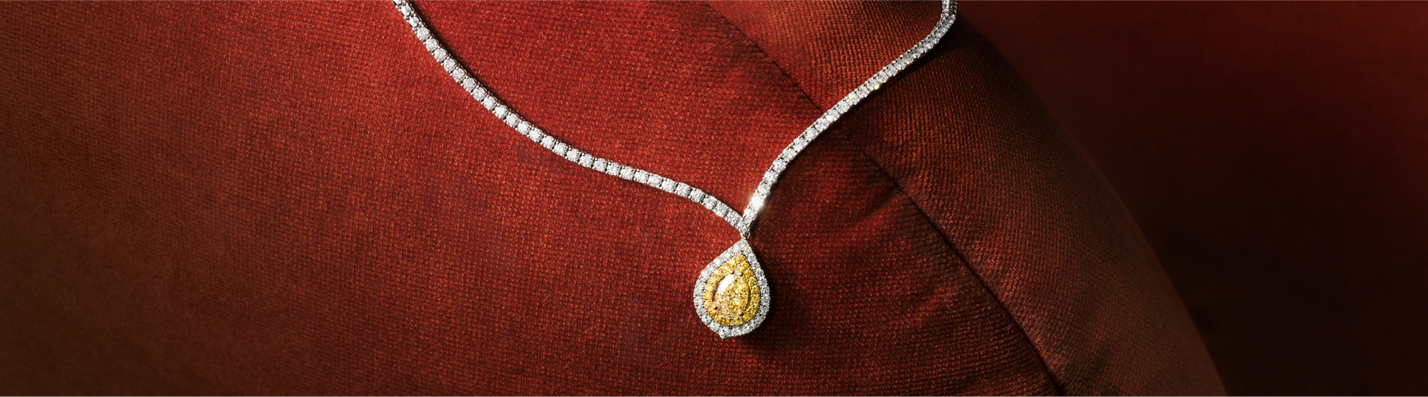 A silver ring with a large oval yellow diamond surrounded by smaller white diamonds is displayed on a dark green background with the text Yellow Diamonds.